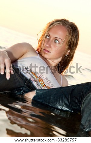 Sexy woman lying in the sea in wet clothes.