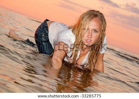 Sexy woman posing in the sea in wet clothes.
