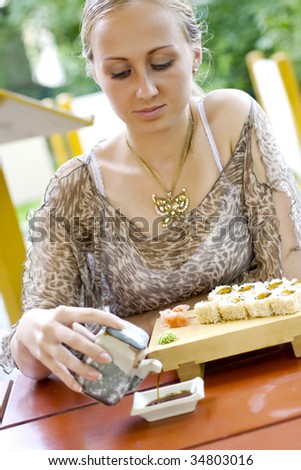 Beautiful woman eating sushi in the restaurant.