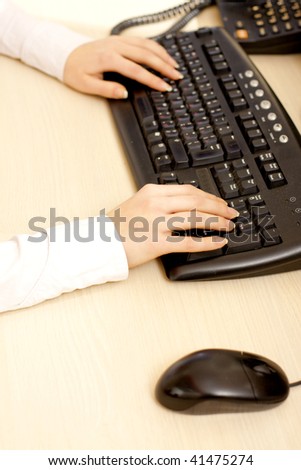 Woman hand on keyboard in office interior.