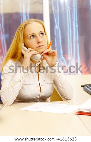 Photo of businesswoman talking by phone with pen in her hand..