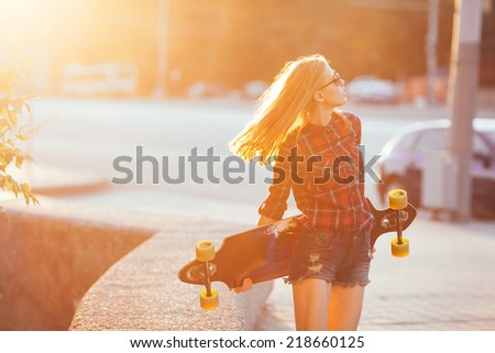 Sport fashion girl posing in sunset  with skateboard