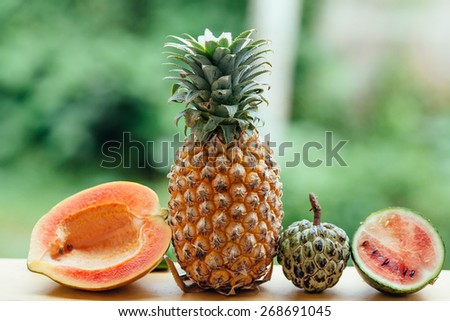 Assortment of fruits on green background. Exotic fruits variety on natural table. Sliced fresh fruits on table