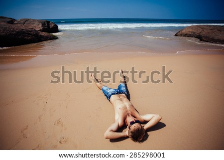 Shirtless male model sunbathing.Top view of  young man relaxing on beach.