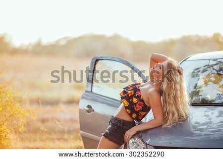 happy young woman with car - sexy rich lady driver with long blond healthy hair at automobile .summer portrait . beautiful slim fashion girl posing near car