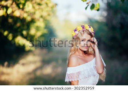 Portrait of blonde girl wearing  white dress with flower wreath in the forest . forest Nymph