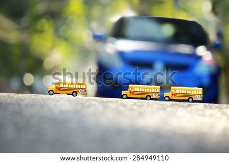 Yellow school buses toy model the road crossing.Shallow depth of field composition and  afternoon scene.