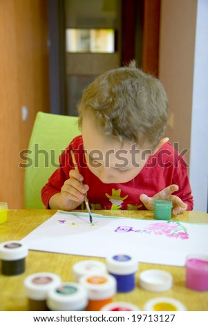 child drawing picture by artistic paints