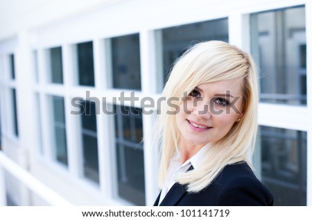 Attractive young blonde woman standing in front of a white framed window facade which gives the image strong architectural perspective
