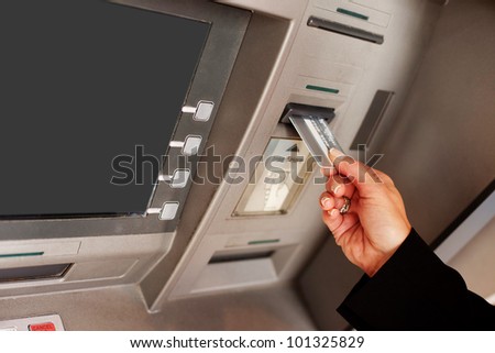 Cropped view of a female hand inserting a bank card into an ATM to begin a financial transaction