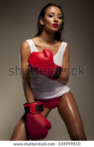 Seductive woman boxer glistens with sweat as she takes a break from traning at the gym
