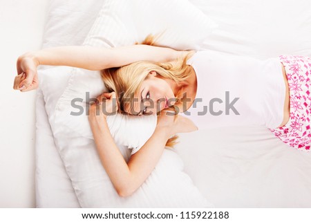 Beautiful woman stretching her arms above her head in bed as she wakens from a nights sleep