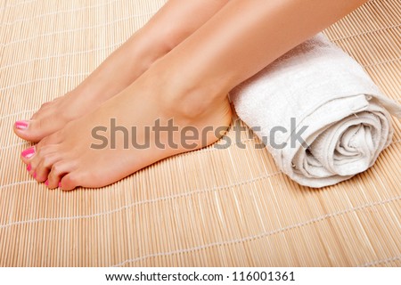 Womans feet with a rolled towel behind the ankles as she waits for a beautician to complete a beauty treatment at a spa
