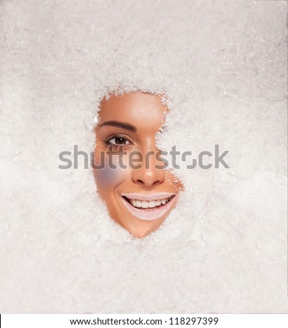 Face of a beautiful woman covered in fresh white winter snow wearing white lipstick reminiscent of a fantasy ice maiden or princess