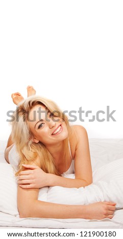 Fresh studio portrait of a gorgeous vivacious blonde woman lying on her bed in lingerie facing the camera laughing with plenty of copyspace overhead