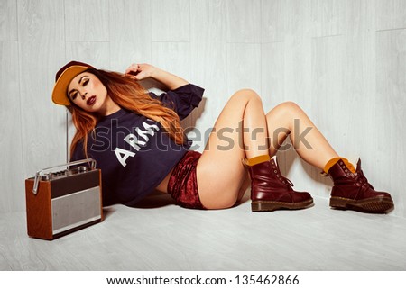 Studio shot of a hot brunette model lying on the floor, listening to an old radio.