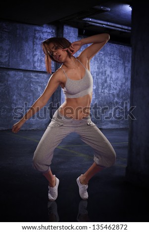 Agile young female hip hop dancer performing her routine on a carpark background