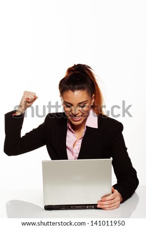 Frustrated businesswoman punching her laptop sitting at her desk with her fist raised in the air and the computer open in front of her