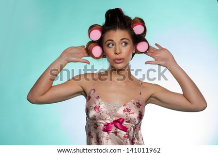 Portrait of a vain pretty young woman wearing a flowery satin summer pajama showing her hair rollers