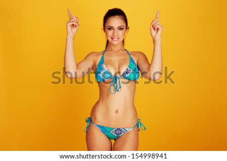 Looking up woman wearing two piece bikini pointing up her hands