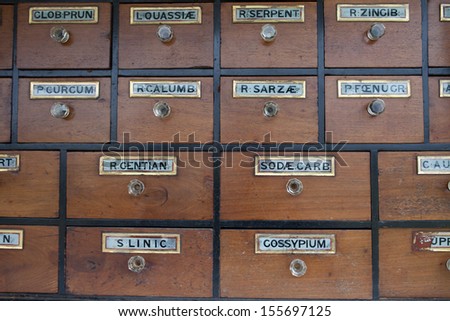 Old wooden cabinet of rows of drawers with vintage labels detailing the contents