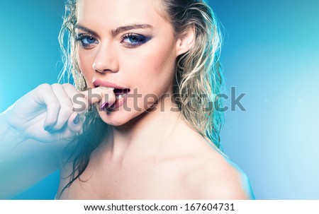 Beautiful blond woman with wet hair and bare shoulders biting her finger and giving the camera a seductive sultry look