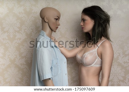 Beautiful young model with a mannequin standing face to face as she models a sexy see-through bra