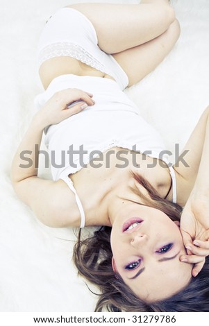 Young woman laying bed portrait close-up pink make-up