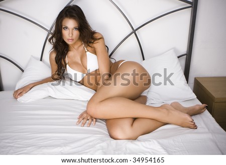 Young brunette sexy glamour woman in white bikini on the bed