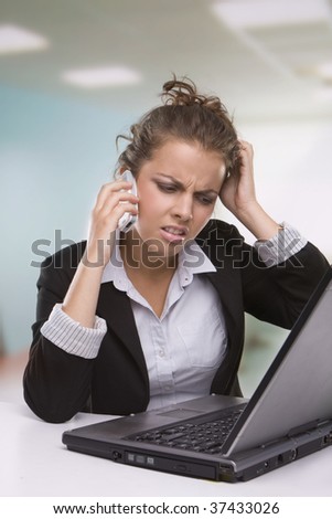 Portrait of tired secretary working in office speaking over the phone and using laptop
