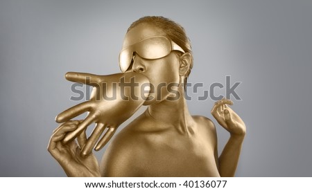 topless gold body-painting on a brunette girl with a funky hairstyle