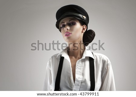 Portrait of beautiful teenager with peak-cap on her head touching a white shirt