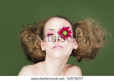 Woman with flower on eye and fluffy hair.