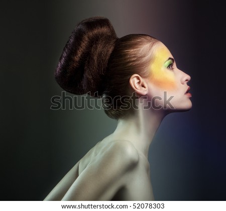 A portrait of a glamorous woman with a creative orange makeup on the sides of her face.