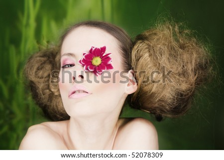 Woman with flower on eye and fluffy hair.