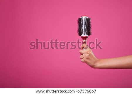 stock photo woman hand holding hairbrush on pink background