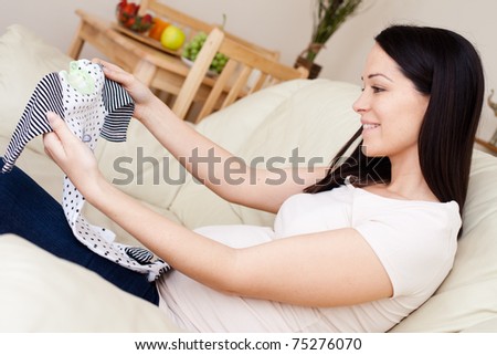 Happy pregnant caucasian brunette  woman waiting arround toys for baby