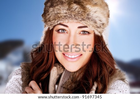 Radiant Winter Beauty. Beauty shot of a radiant smiling woman full of vitality and with a lovely complexion., against blue sky