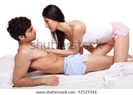 Young Couple lying on top of a bed and staring intently into each others eyes with love.