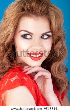 Pretty smiling redhead woman wearing red dress and matching lipgloss glancing sideways.