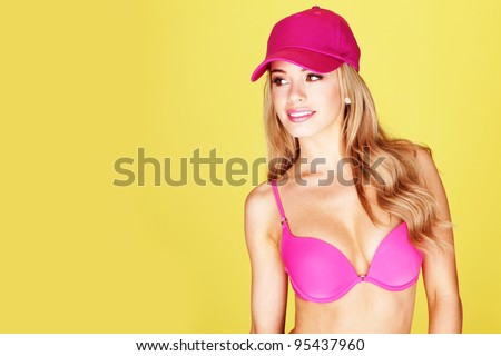 Smiling pretty young blonde woman in a pink bikini and matching peaked cap.