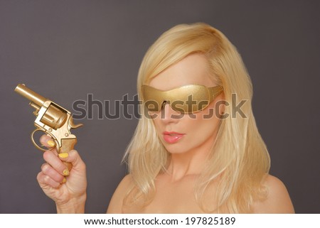 Girl With Blonde Hair wearing Gold shades Holding a Gun.