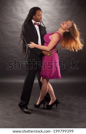young multiracial couple with a dreadlock African American man wearing suit and cute blond woman dancing wearing dress