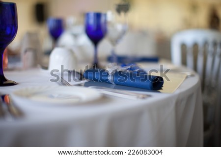 Blue serviette detail on a formal wedding table set with blue and white linen and elegant matching glassware, selective focus with the napkin centered and copyspace