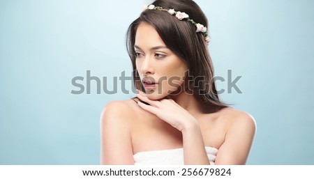 Close up Portrait of Sensual Young Fresh Woman with Hand on the Chin Looking at Left Frame on a Sky Blue Background.