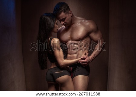 Portrait of a Romantic Young Bodybuilding Couple with Sexy Bodies Posing so Closed Against a Brown Wooden Wall Background