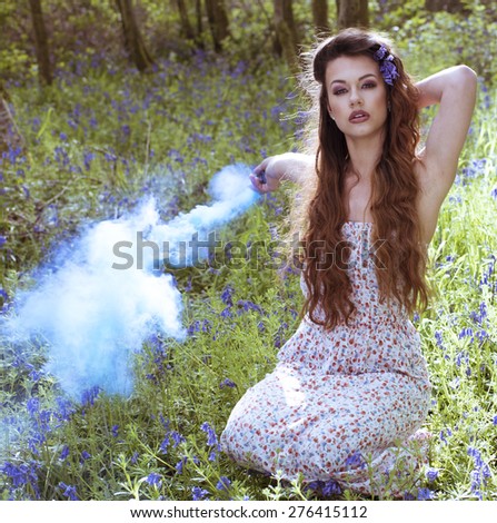 Artistic portrait of a girl in a bluebell forest surrounded by smoke