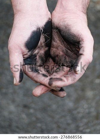 Empty cupped hands dirty of charcoal, concept of low-paid hard work in insalubrious conditions, high-angle close-up