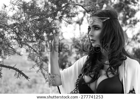 Black and White Head and Shoulders Portrait of Mystical Looking Brunette Woman Wearing Head Band Standing Underneath Flowering Tree