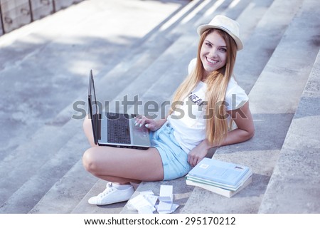 Pretty Young Student with Laptop Computer, Sitting on the Stairs Outside the Building and Smiling at the Camera.